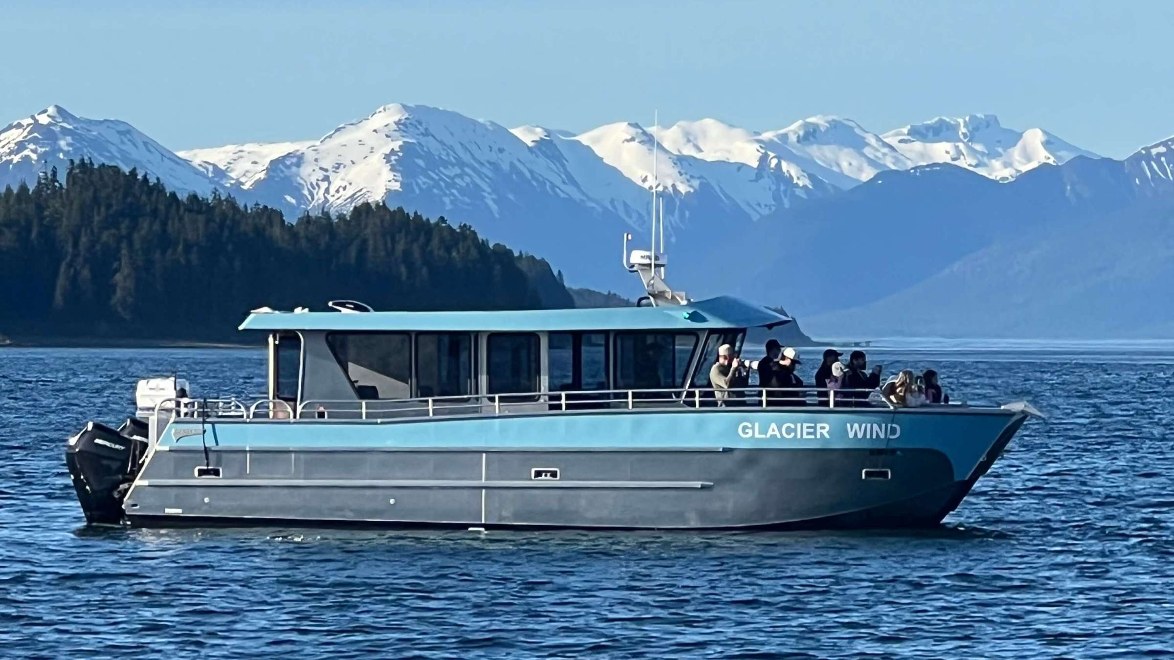 Boat on water with snow-capped mountains in the background.